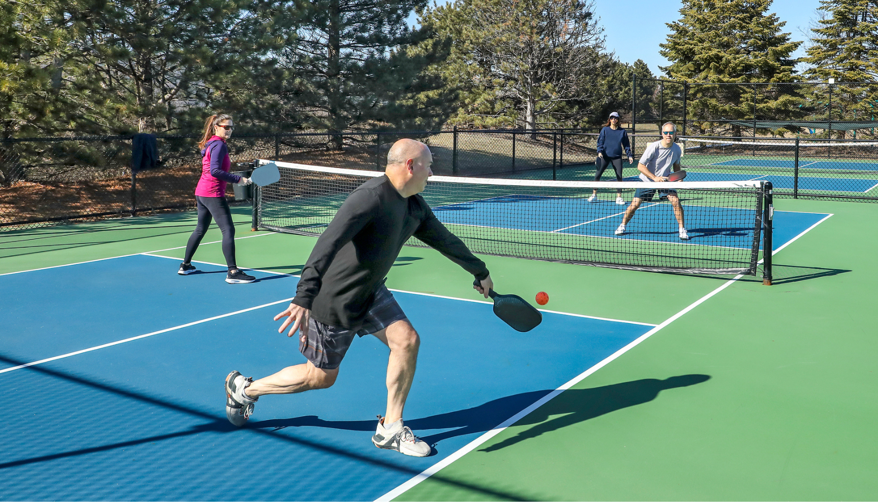 Doubles pickleball players in a dynamic rally, demonstrating teamwork and skillful exchanges on the court.