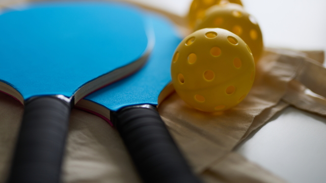 Blue pickleball paddles and yellow pickleballs